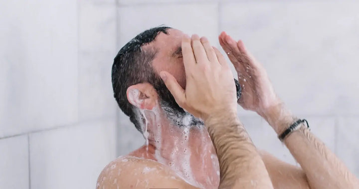 man washing face in shower