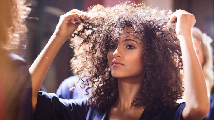 lady with a large afro looking at herself in the mirror