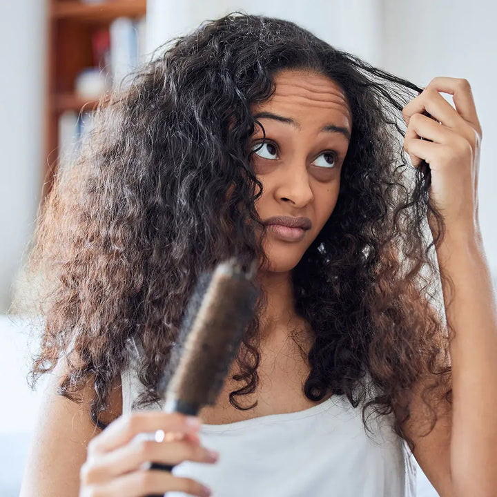 woman touching her curly hair with a disgusted expression 