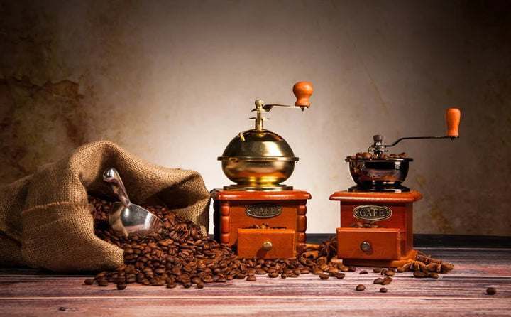 coffee beans spilling out of a coffee bean bag with coffee grinders on the table