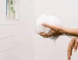 person holding a loofah in the shower 