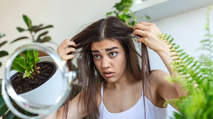 lady looking at her scalp in the mirror 