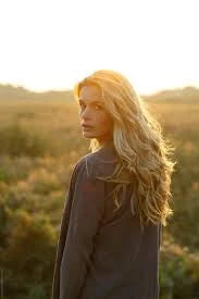 lady looking back with long blonde hair, in a nature backdrop