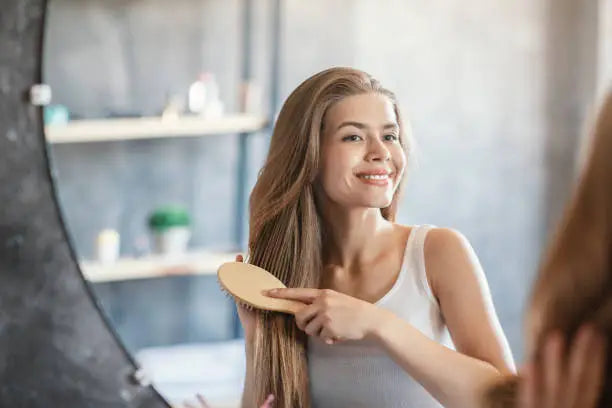 lady smiling at herself in the mirror while brushing her hair