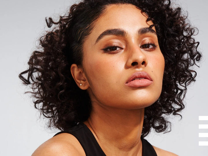 close up of lady with short curly hair and thick eyebrows