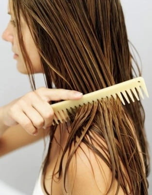 lady combing out her wet hair close up